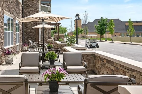 Seating area on the patio with umbrellas and flowers at Anthology of Wildwood