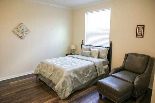 A well-decorated bedroom with a bed, chair, and window.