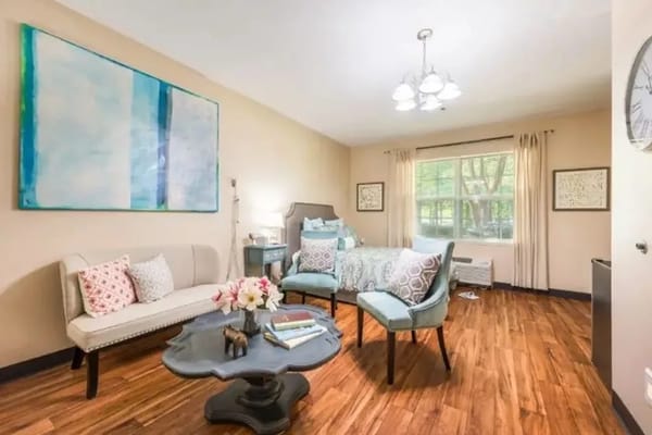Cozy common room featuring a sofa, chairs, and a large window