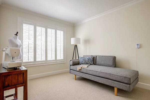 Bright living room with a sofa, sewing machine, and lamp.