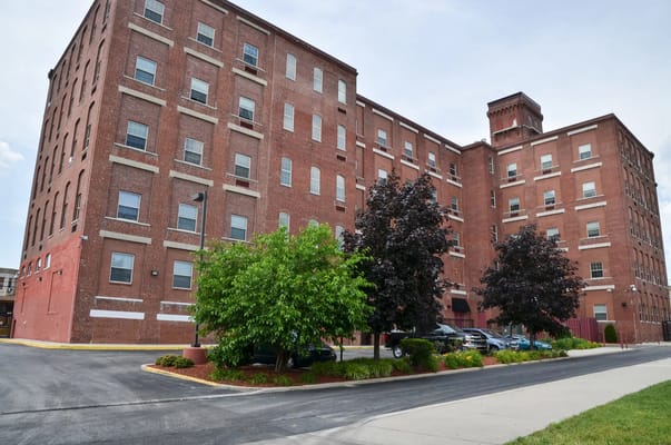Red brick building of Caribe Towers with nearby trees and parking area.