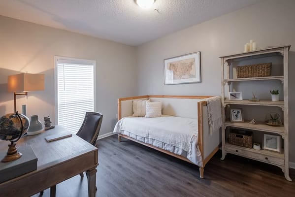 A cozy bedroom with a twin bed, desk, and bookshelf.