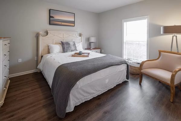 Well-furnished bedroom with a bed, dresser, and chair