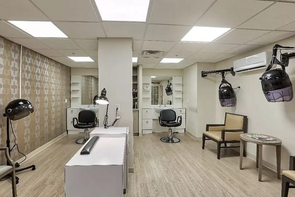 Interior of the salon featuring chairs, mirrors, and hair drying units.
