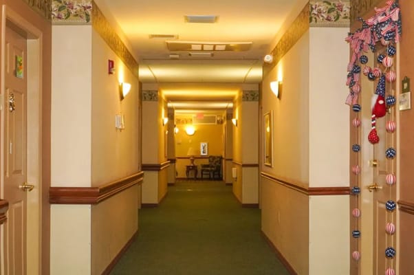 A hallway in The Club at Bartow with decorative lighting and a chair at the end.