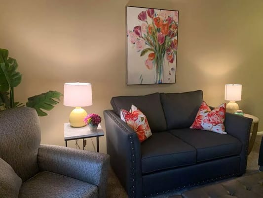 Comfortable living room with a dark sofa, decorative pillows, and a lamp.