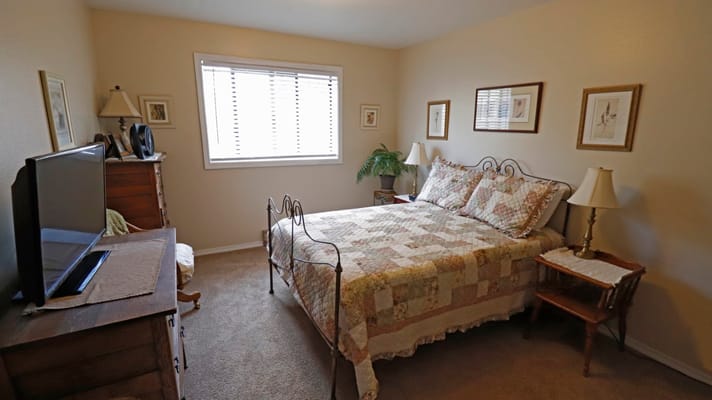 Brightly lit bedroom with decorative quilt and furnishings