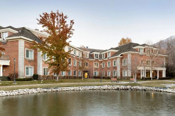 Brick building of Courtyard at Jamestown Assisted Living beside a pond