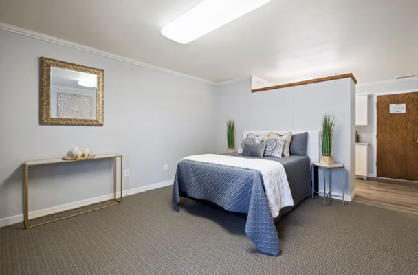 A well-decorated bedroom with a bed, mirror, and decorative items.