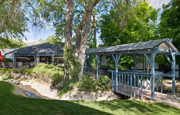 A wooden bridge over a small stream surrounded by greenery at Cove Point Retirement.