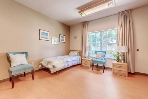 A cozy bedroom featuring a bed, two side tables, and a window with natural light.