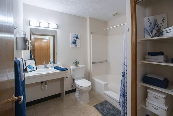 Bright bathroom featuring shower, toilet, and sink with decorative towels