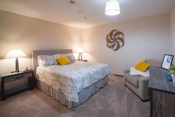 A well-furnished bedroom with a bed, side tables, and a cozy chair.