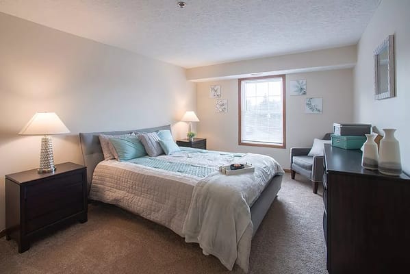 A well-furnished bedroom with a bed, nightstands, and soft lighting.
