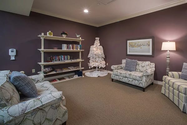 Lounge area with bookshelves and a Christmas tree at Danbury Senior Living.