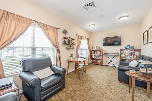 A cozy living room with comfortable seating, bookshelves, and a television.
