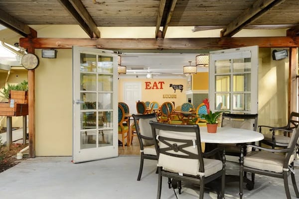 Outdoor dining area leading into a brightly decorated kitchen.