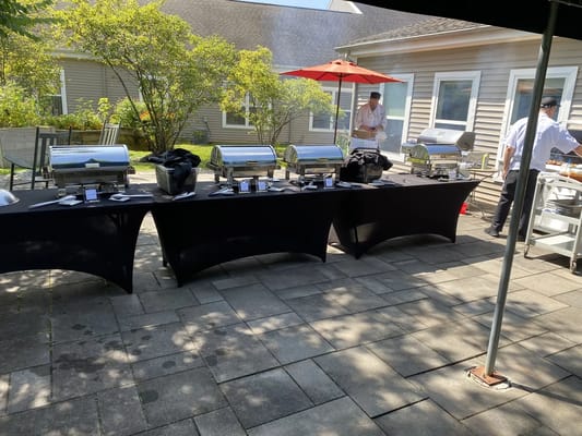 Outdoor dining setup with food stations and staff members.
