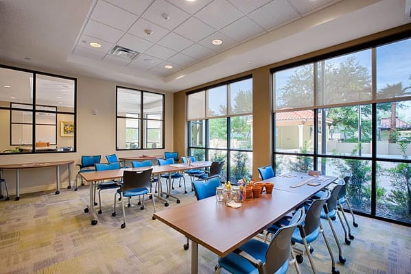 Bright common area with tables and chairs in Excellence Senior Living.