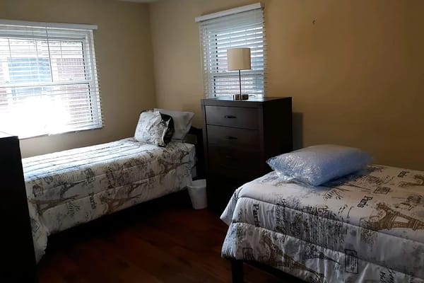 Private resident room with two beds and a dresser