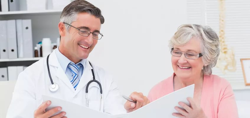 A doctor and a senior woman reviewing documents together, smiling.
