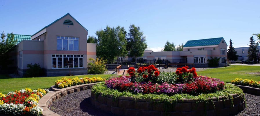 Exterior view of Denali Center with colorful flower beds
