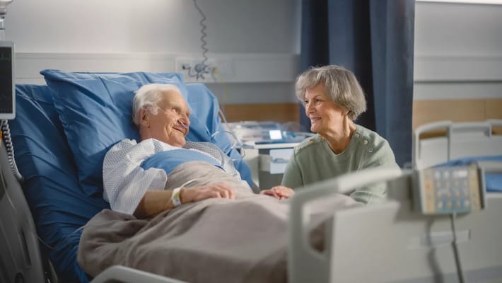 A caregiver interacts with a resident in a hospital room