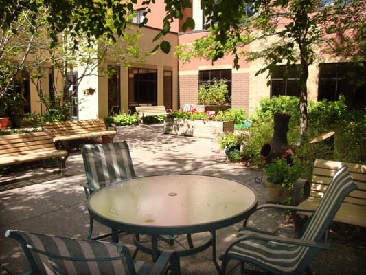 A serene courtyard featuring benches, a table, and flower beds.