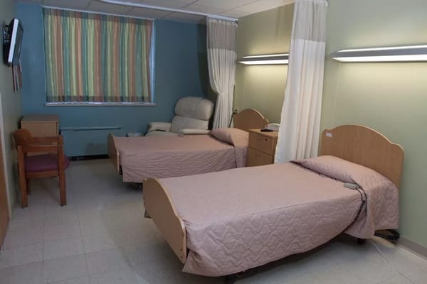 A cozy resident room with two beds and a recliner