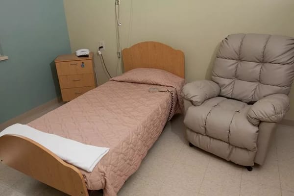 A simple resident room with a bed and armchair