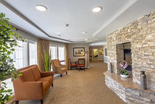 Cozy lounge area with two chairs, a stone fireplace, and natural light.