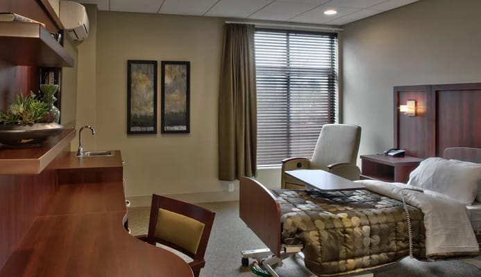 Cozy bedroom with hospital bed, sitting area, and natural light