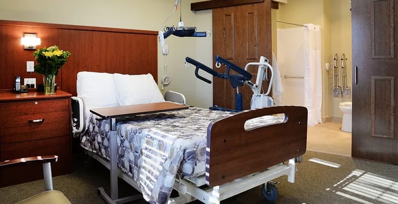 A hospital room featuring a bed, bedside table, and bathroom facilities.