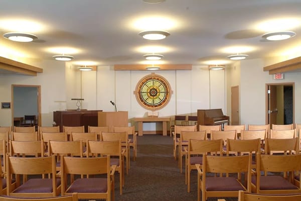 Interior view of a community gathering space with chairs and a stained glass window