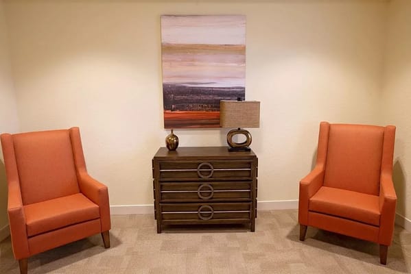 Cozy seating area with two orange chairs and artwork