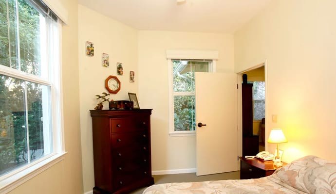 A cozy private resident room with a window and dresser