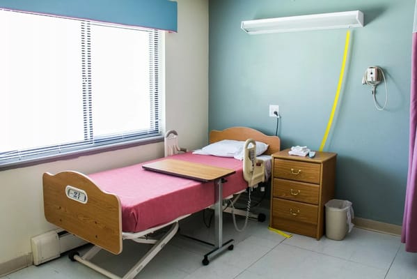 Private resident room with a hospital bed and nightstand