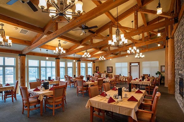 Bright dining room with wooden beams and tables set for meals.