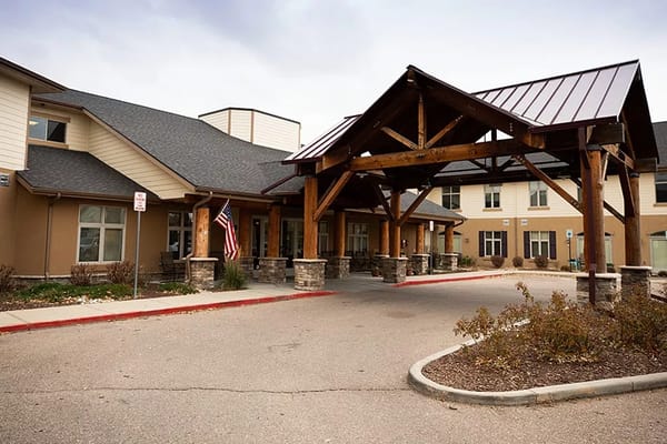 Entrance of MeadowView of Greeley with wooden awning and flag.