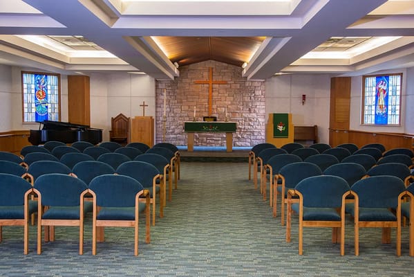 An interior chapel with rows of pews and stained glass windows