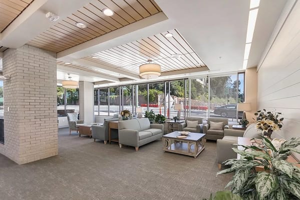 A spacious and bright lobby with comfortable seating and plants.