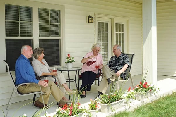 Four senior residents socializing on a patio with drinks.