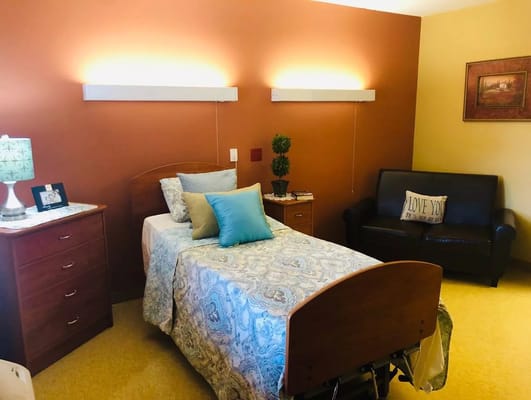 A furnished bedroom with a bed, dresser, and a cozy seating area.