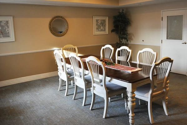 A dining room with a long table and white chairs.