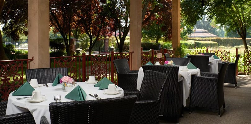 Tables set for dining on the patio surrounded by greenery