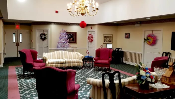 A cozy lobby area with pink chairs and a striped sofa, decorated for the holidays.