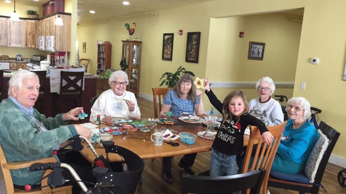 Seniors and a child engaged in a craft activity at a dining table.