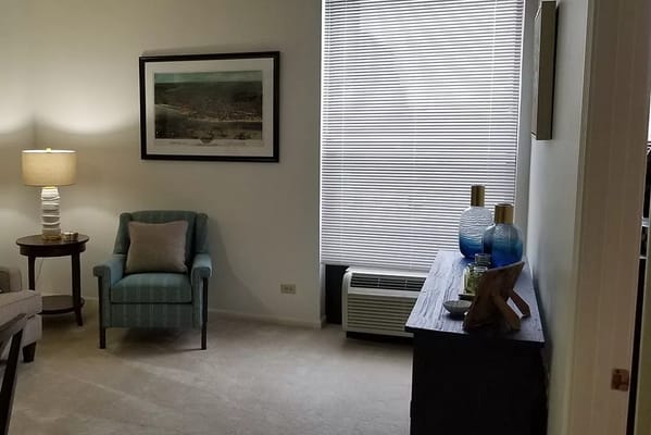 Comfortable living room featuring a chair, lamp, and decorative items.