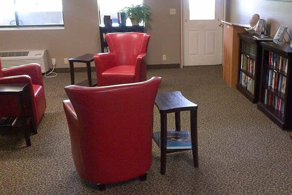 A cozy common area with red chairs and a small table