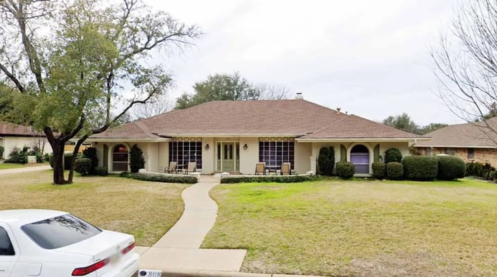 Exterior view of an assisted living facility with a landscaped yard.